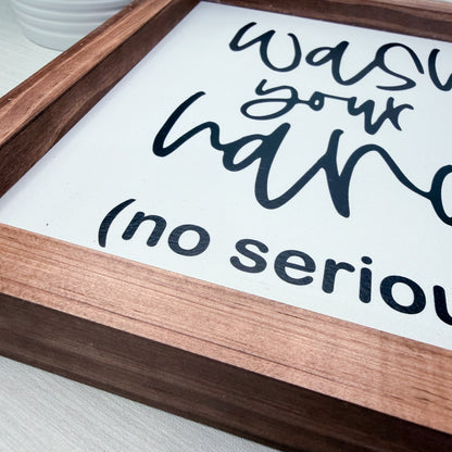 Wooden sign with text 'Was your hand' on a white background