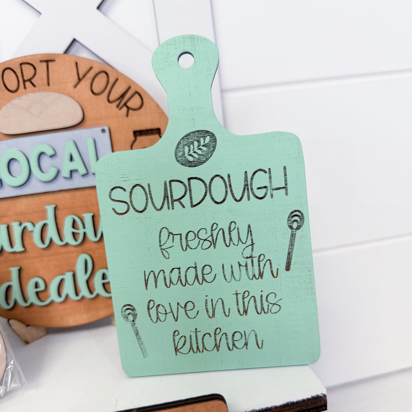 Decorative sign with 'Sourdough freshly made with love in this kitchen' text on a white surface.