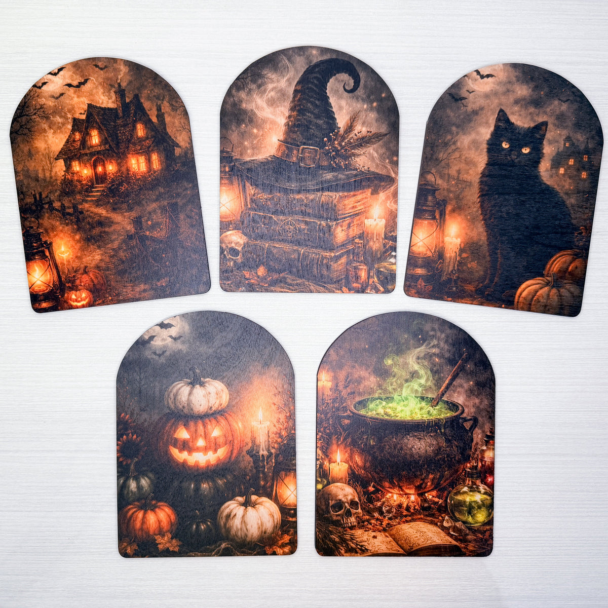 Five arched Halloween-themed decorative tags or labels with spooky illustrations, including a haunted house, witch hat, black cat, pumpkins, and cauldron, displayed on a light gray background.