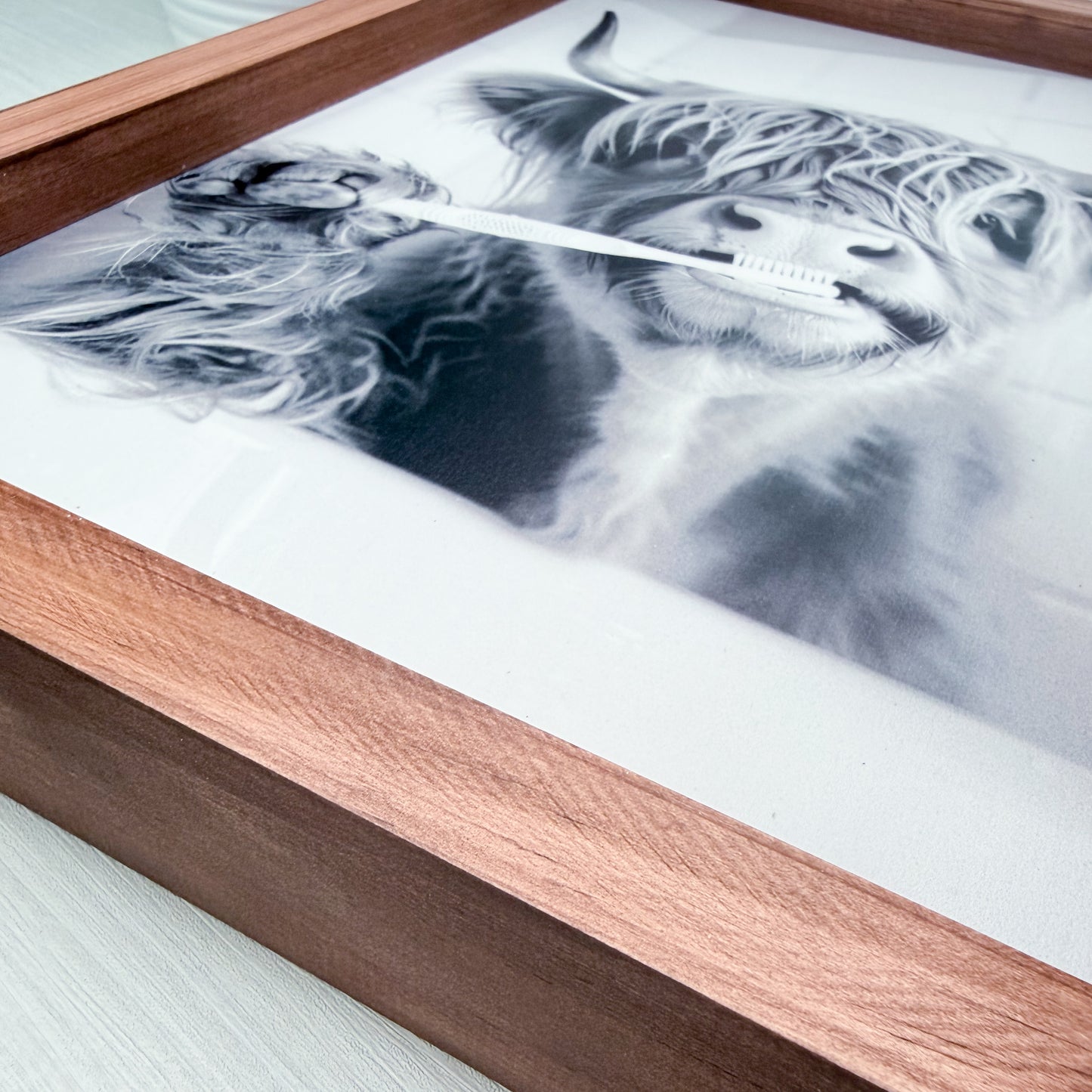 Framed artwork of a lion's face with a wooden frame on a light surface.