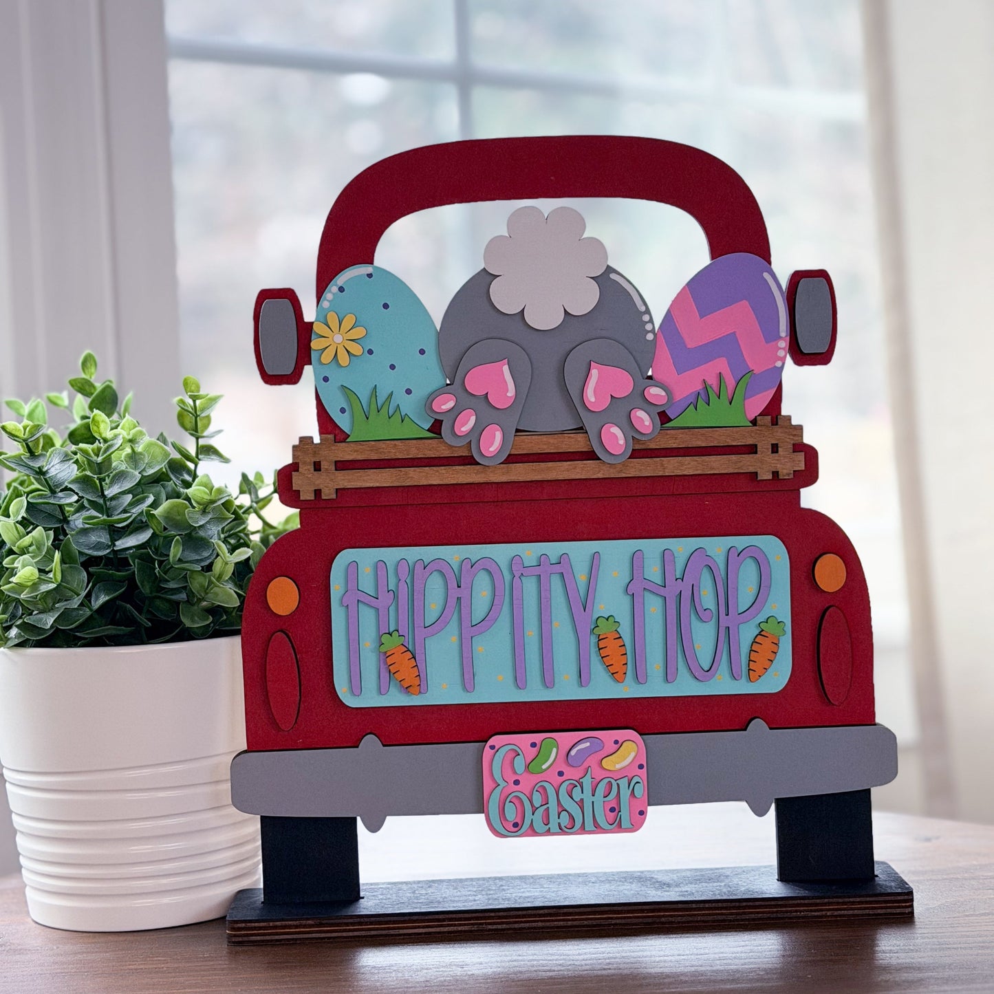 Decorative sign of a red truck with Easter-themed decorations on a wooden stand.