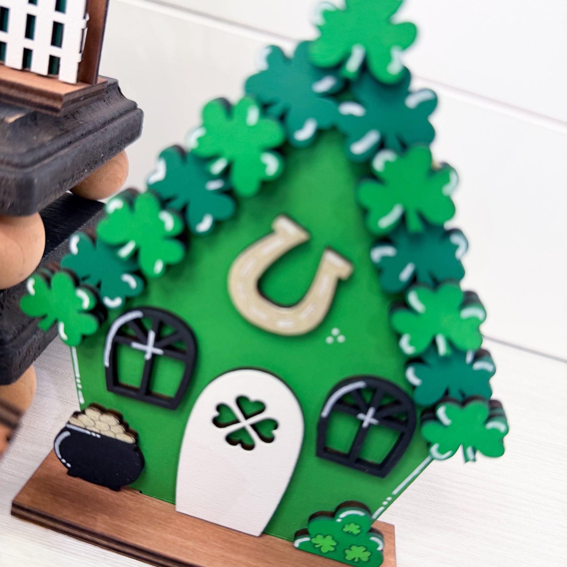 Decorative green house with shamrocks, a horseshoe, and other symbols on a white background