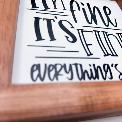 Wooden frame with a white background and black text, featuring phrases like 'I'm fine', 'IT'S FINE', and 'everything's fine'.