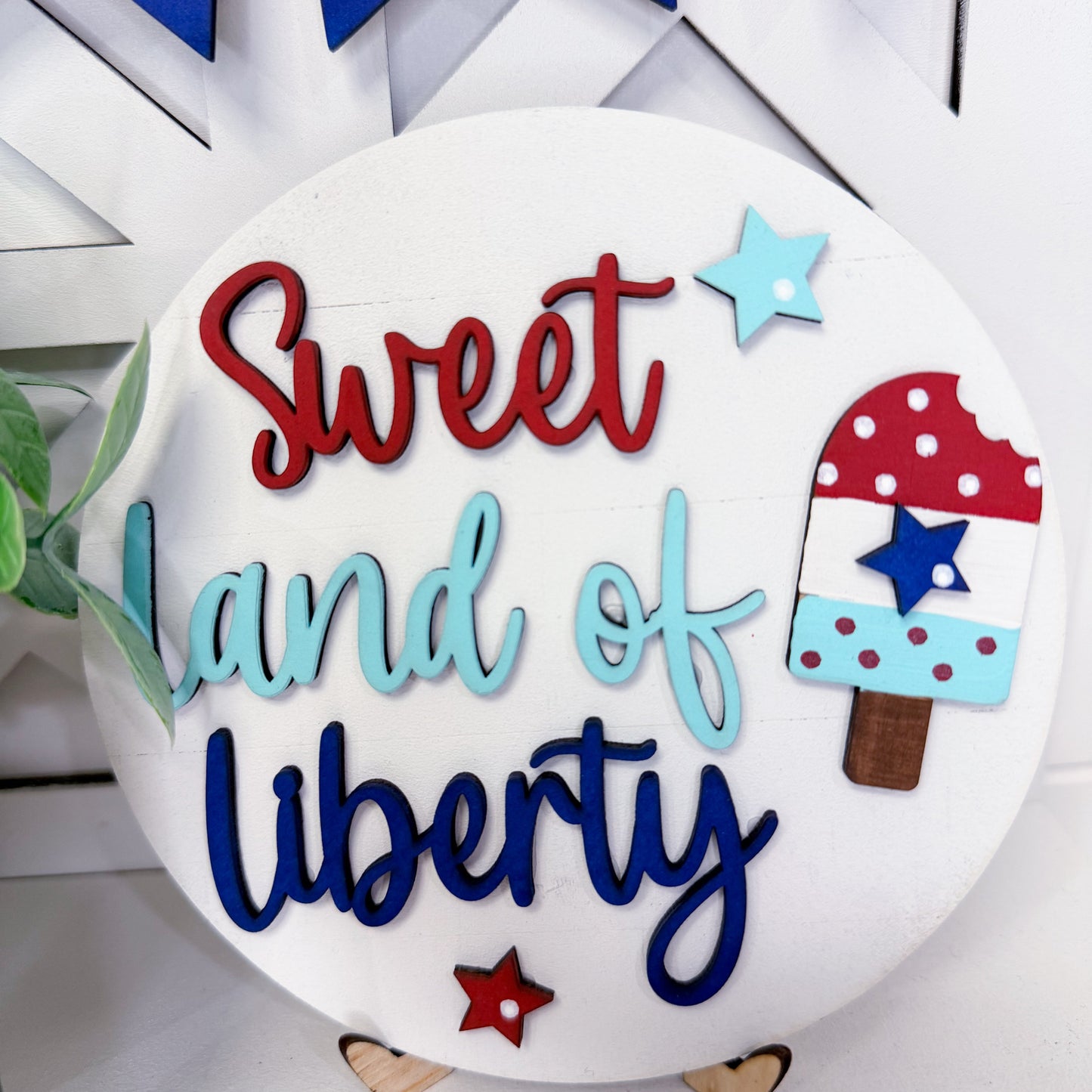 Decorative sign with 'Sweet Land of Liberty' text and ice cream popsicle design.