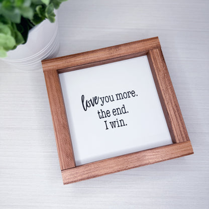 Wooden frame with a white sign inside displaying text on a light gray background