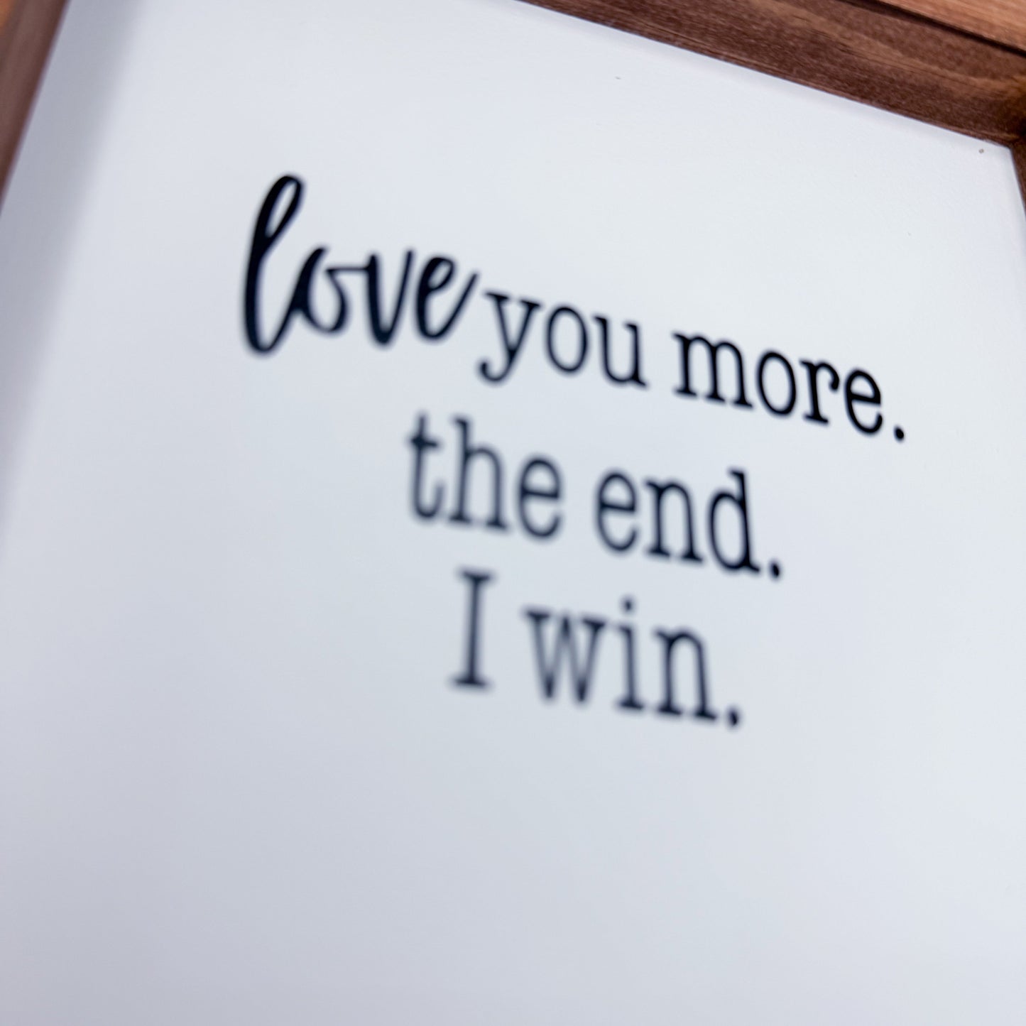 Text 'love you more. the end. I win.' on a white background with a wooden frame.