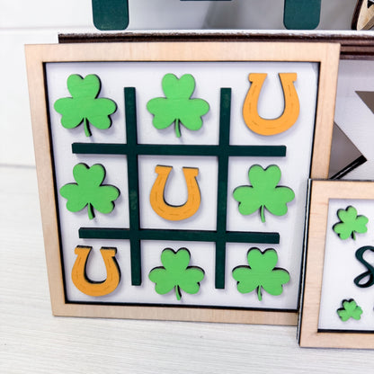 Tic-tac-toe game with green clover and orange horseshoe pieces on a white background