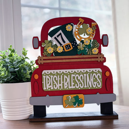 Decorative sign shaped like a red truck with 'Irish Blessings' text, shamrock design, and decorative elements on a wooden stand.