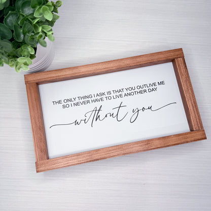 Wooden-framed sign with romantic quote on a white background, plant to the side.