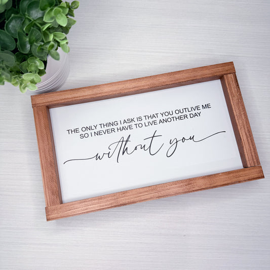 Wooden-framed sign with romantic quote on a white background, plant to the side.