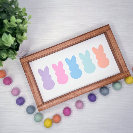Framed artwork with colorful bunny shapes on a white background, surrounded by decorative items.