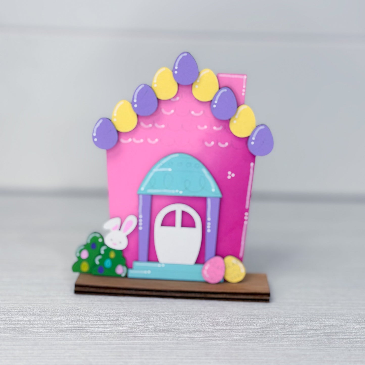 Colorful toy house with Easter-themed decorations on a gray background