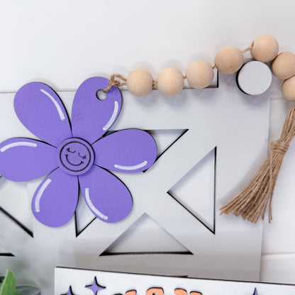 Purple flower-shaped decoration with a smiley face on a white background