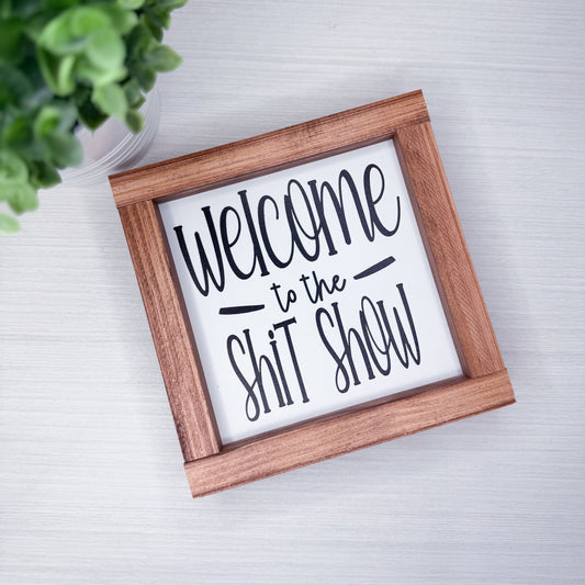 Wooden-framed sign with humorous text on a light background