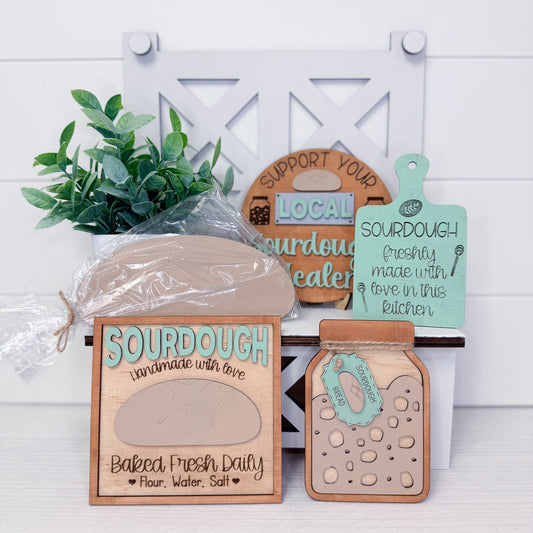Wooden packaging with 'Sourdough' text, a plant, and decorative signs on a white background