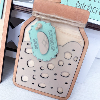 Decorative sign with a mason jar design and 'Sourdough Bread' label on a white surface.