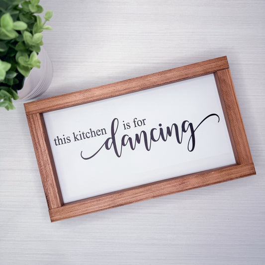 Wooden-framed sign with 'this kitchen is for dancing' text on a white background