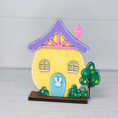 Colorful house-shaped object with a rabbit door on a gray background