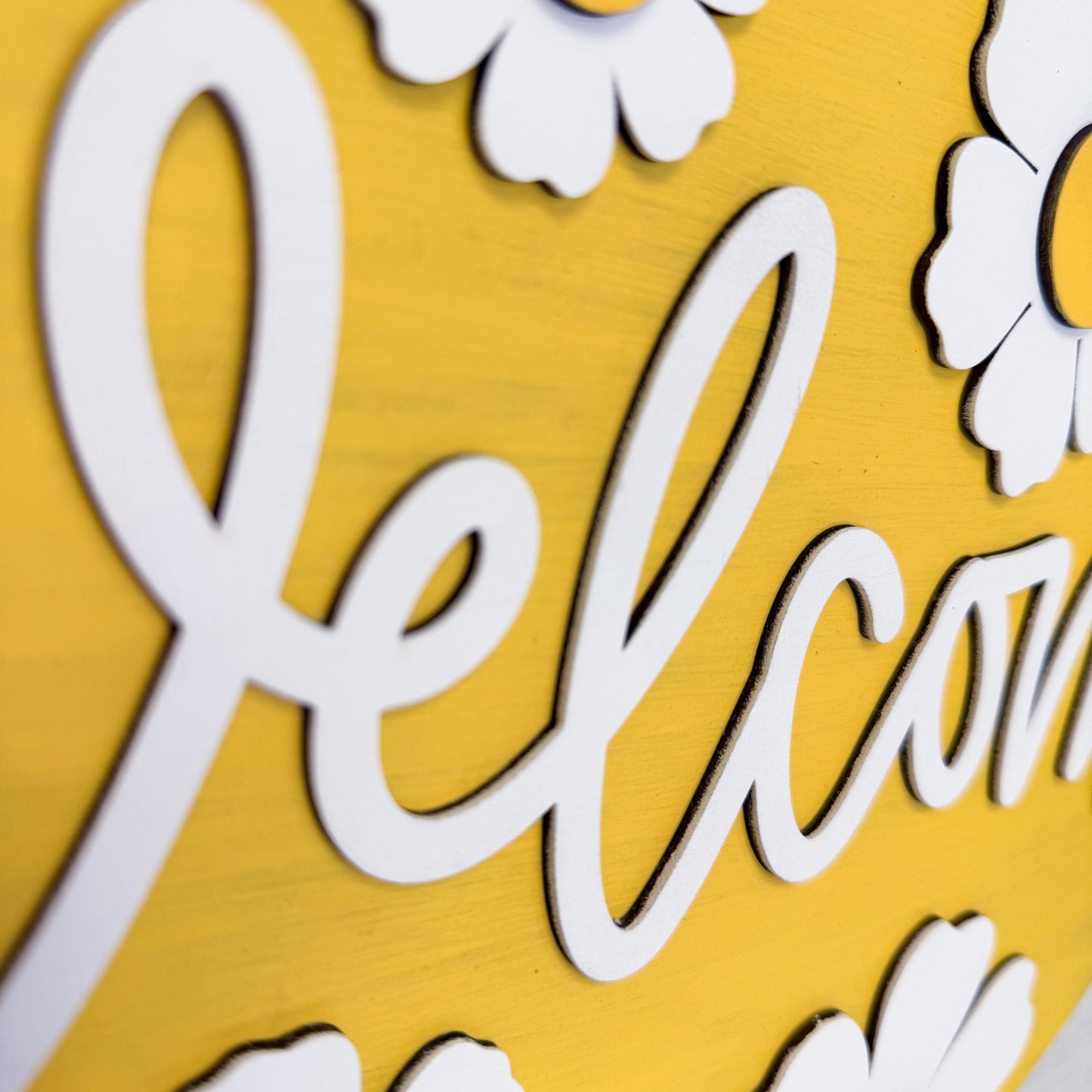White 'Welcome' text on a yellow background with floral decorations